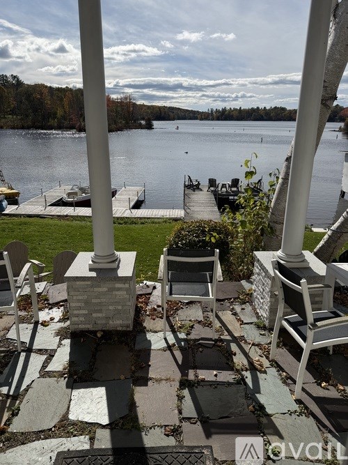 A view of a lake from a patio with chairs and tables.