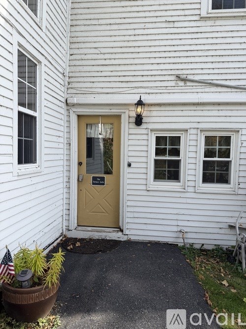 A white house with a yellow door and a small porch.