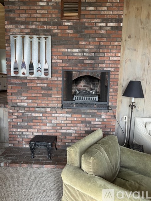 A living room with a green couch and a brick wall.