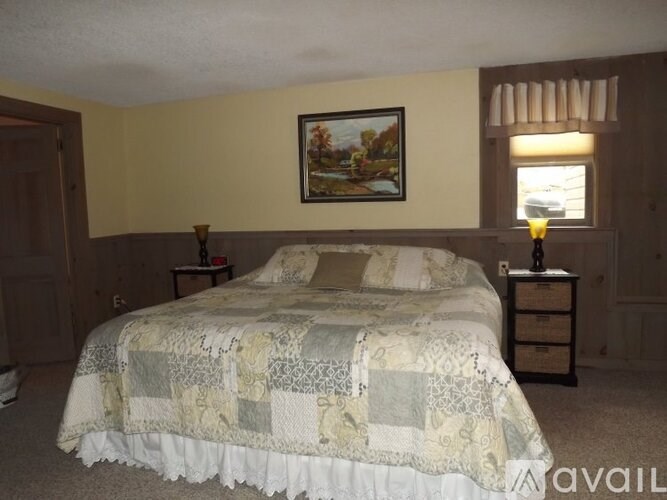 A bed with a quilt and pillow is in a room with a picture on the wall.