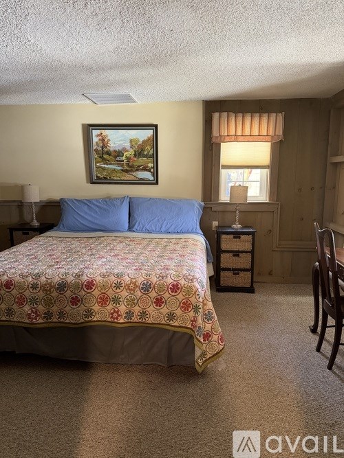 A bedroom with a bed, chair, and painting on the wall.