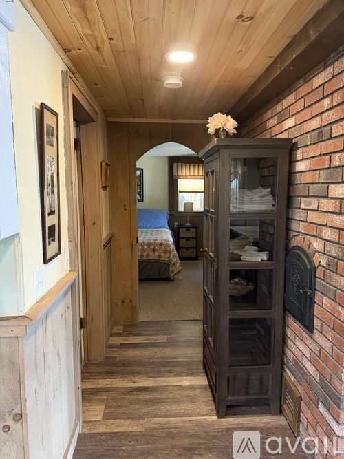 A hallway with a wooden floor and a brick wall.