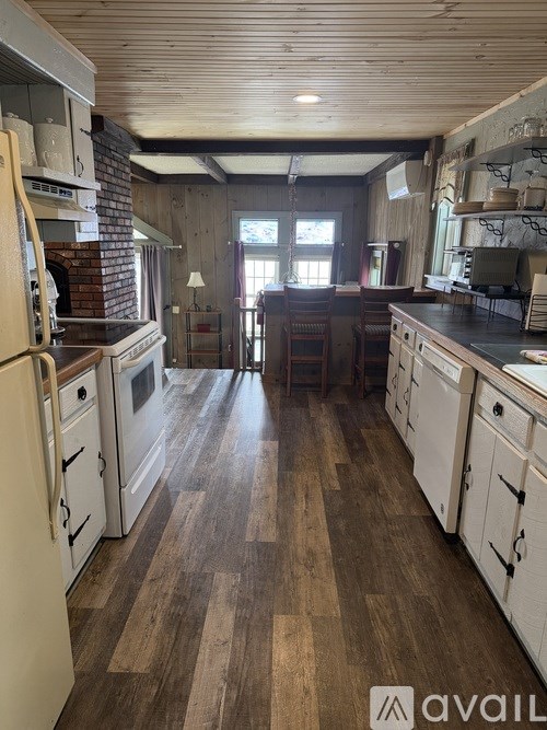 A kitchen with wooden floors and white appliances.