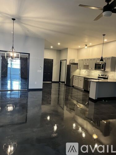 A spacious kitchen and living room with a marble floor and modern appliances.