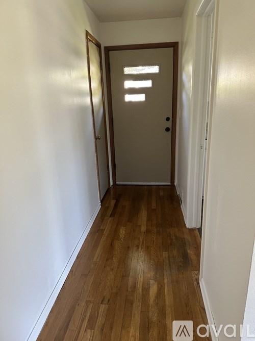 A hallway with a wooden floor and a closed door.