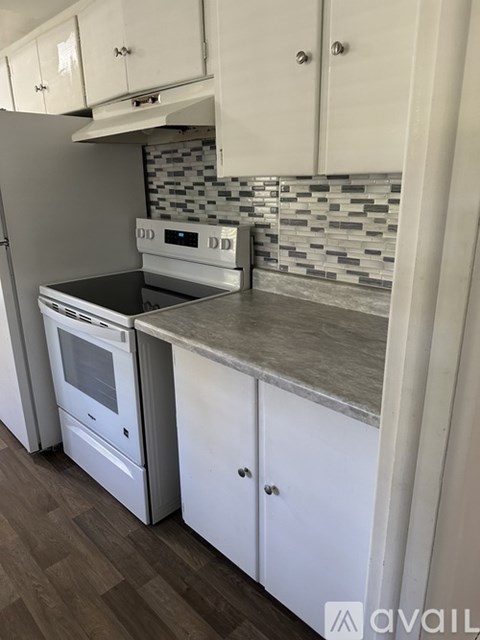 A kitchen with white cabinets and a stove top oven.