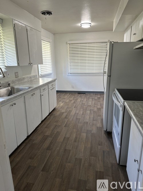 A kitchen with white cabinets and a wooden floor.