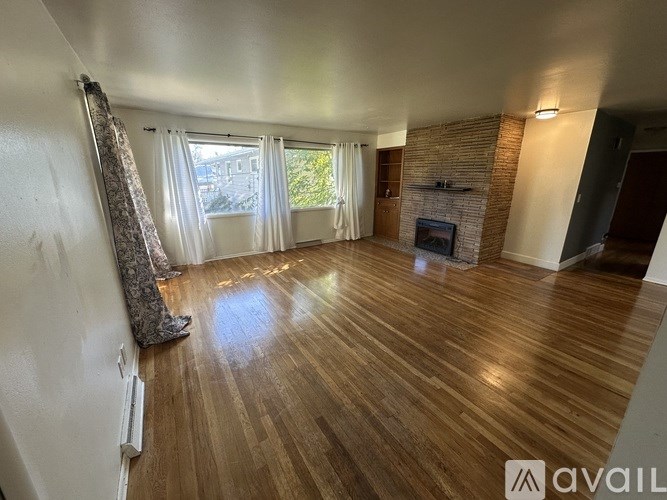 A room with wooden floors and a fireplace with a window in the background.