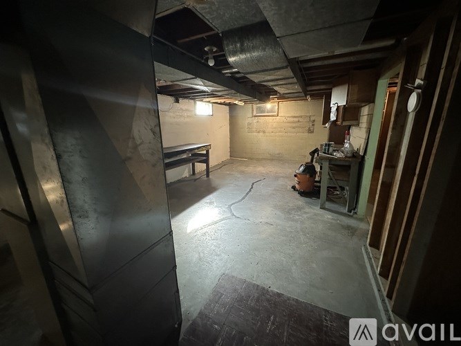 A dark, unfinished basement with a refrigerator and a workbench.
