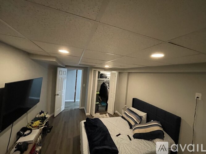 A bedroom with a bed, a television, and a door leading to a balcony.