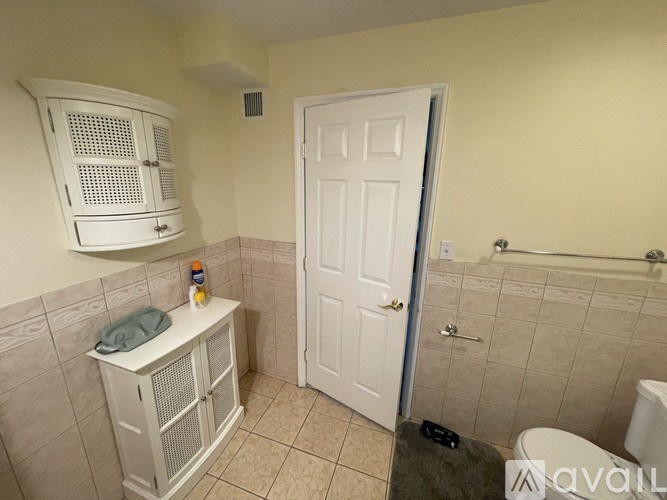 A bathroom with a white door and a white cabinet with a window.