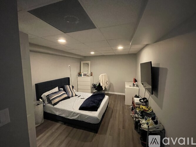 A bedroom with a bed, nightstand, and a TV on the wall.
