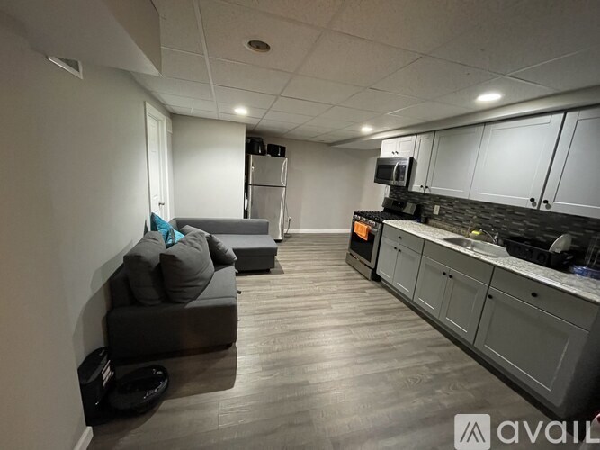 A living room with a grey couch and a black hat on the floor.