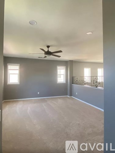 A room with a ceiling fan and two windows.