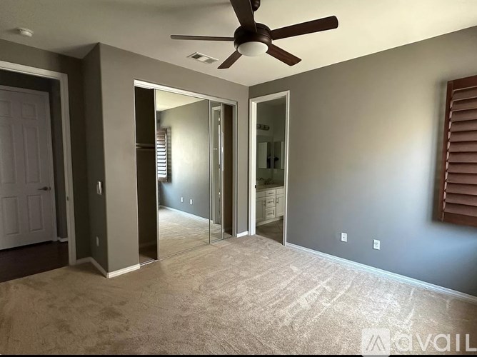 A room with a ceiling fan and carpeted floor.
