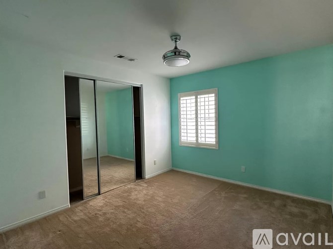 A room with a carpeted floor, a ceiling fan, and a sliding glass door.