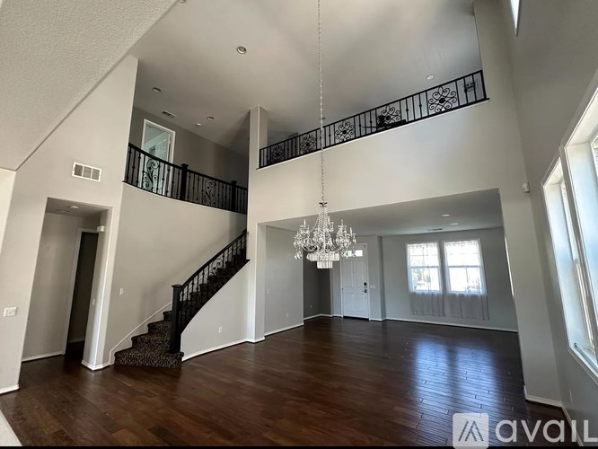 A spacious living room with a staircase and a chandelier.