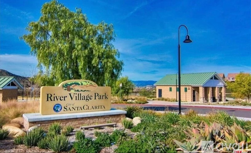 A sign for River Village Park in Santa Clarita stands in front of a building.