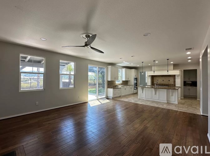 A spacious room with wooden flooring and a ceiling fan.