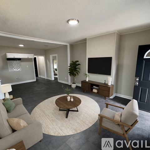 A living room with a sofa, a chair, a coffee table, and a television.