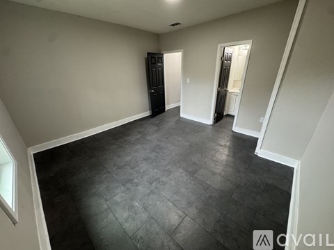 A spacious room with a dark floor and white walls.