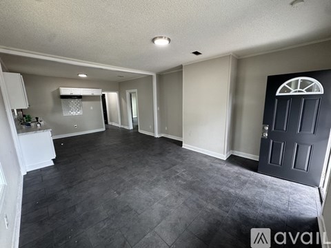 A spacious room with a black door and a grey floor.