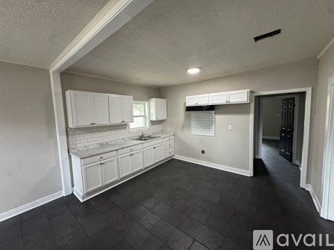 A kitchen with white cabinets and a black floor.