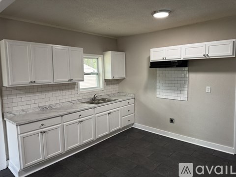 A kitchen with white cabinets and a marble countertop.