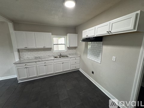 A kitchen with white cabinets and a black floor.