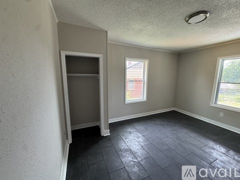 A room with a black tile floor and a window showing a red building outside.