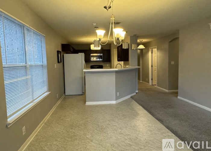 A spacious living room with a kitchenette and a chandelier.