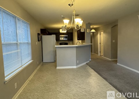 A spacious living room with a kitchenette and a chandelier.