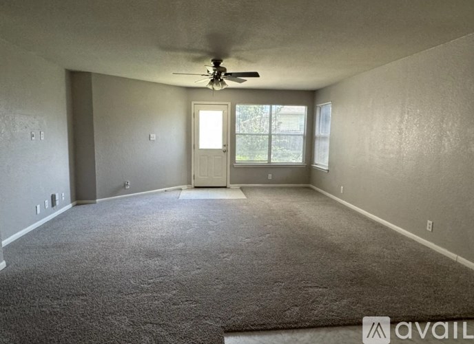 A spacious room with a carpeted floor and a ceiling fan.