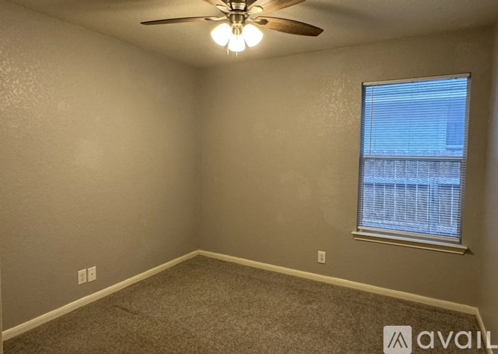A room with a ceiling fan and a window with blinds.