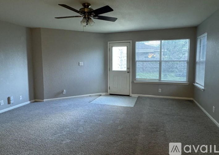 A room with a ceiling fan and a door leading to a balcony.