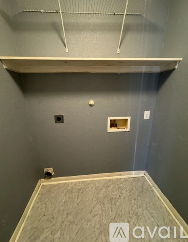 A room with a grey wall and a white shelf.