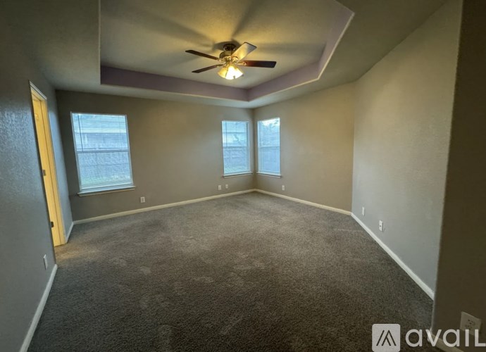 A room with a ceiling fan and two windows.