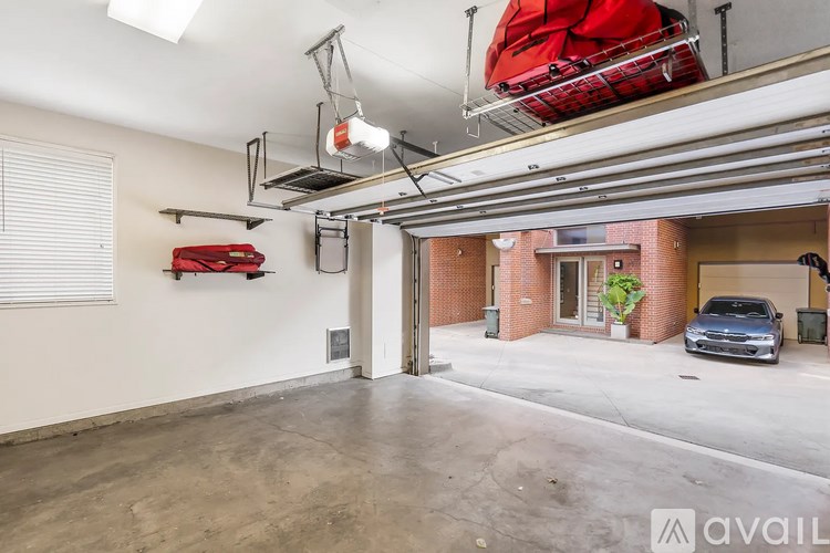 A garage with a red object hanging from the ceiling and a car parked in the driveway.