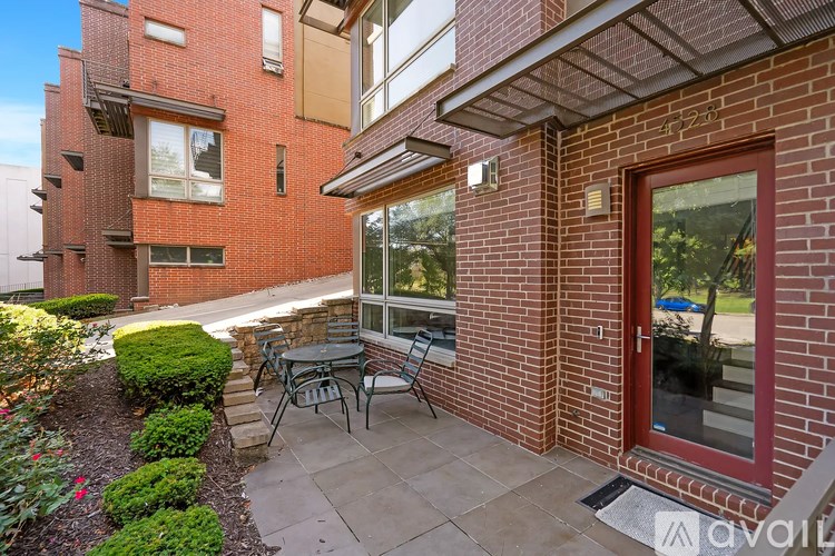 A patio with a table and chairs is in front of a brick building.