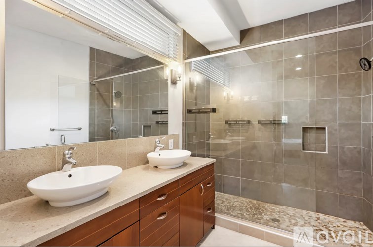 A modern bathroom with a double sink vanity and a walk-in shower.