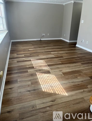 A room with wooden flooring and a window on the left side.