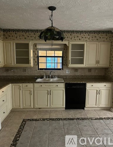 A kitchen with a black dishwasher and a window.