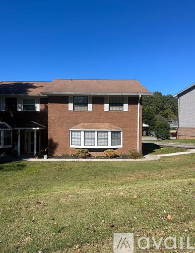 A house with a brown brick exterior and a brown roof with a white window.