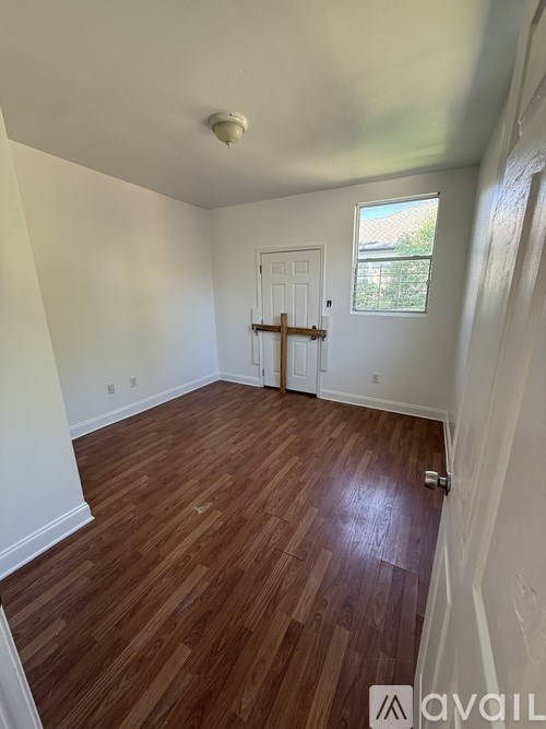 A room with wooden flooring and white walls.