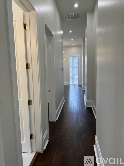 A hallway with white doors and a wooden floor.
