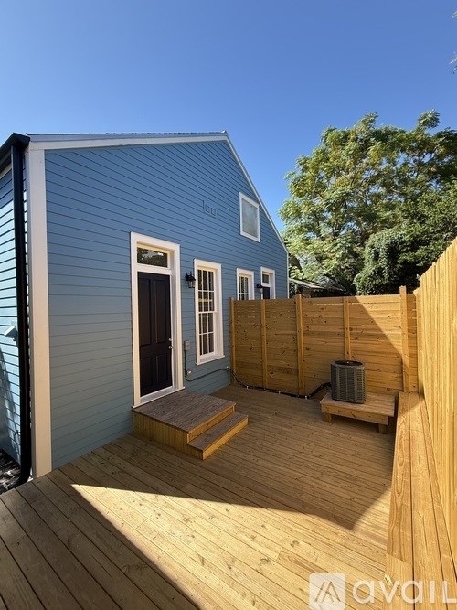 A small blue house with a wooden deck and a wooden fence.