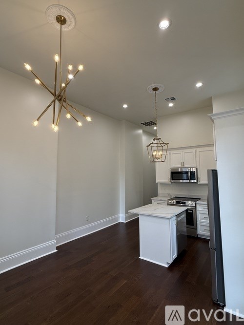 A kitchen with a white island and a hanging light fixture.