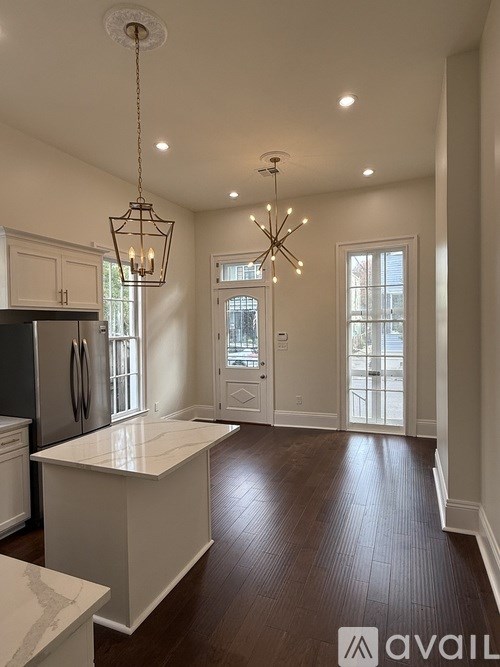 A kitchen with a white island and a chandelier hanging from the ceiling.
