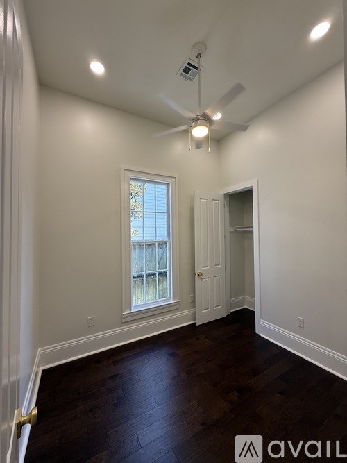 A room with a ceiling fan and a window with a view of a fence.