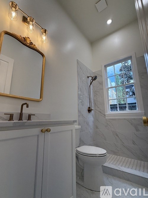 A white bathroom with a toilet, sink, and mirror.